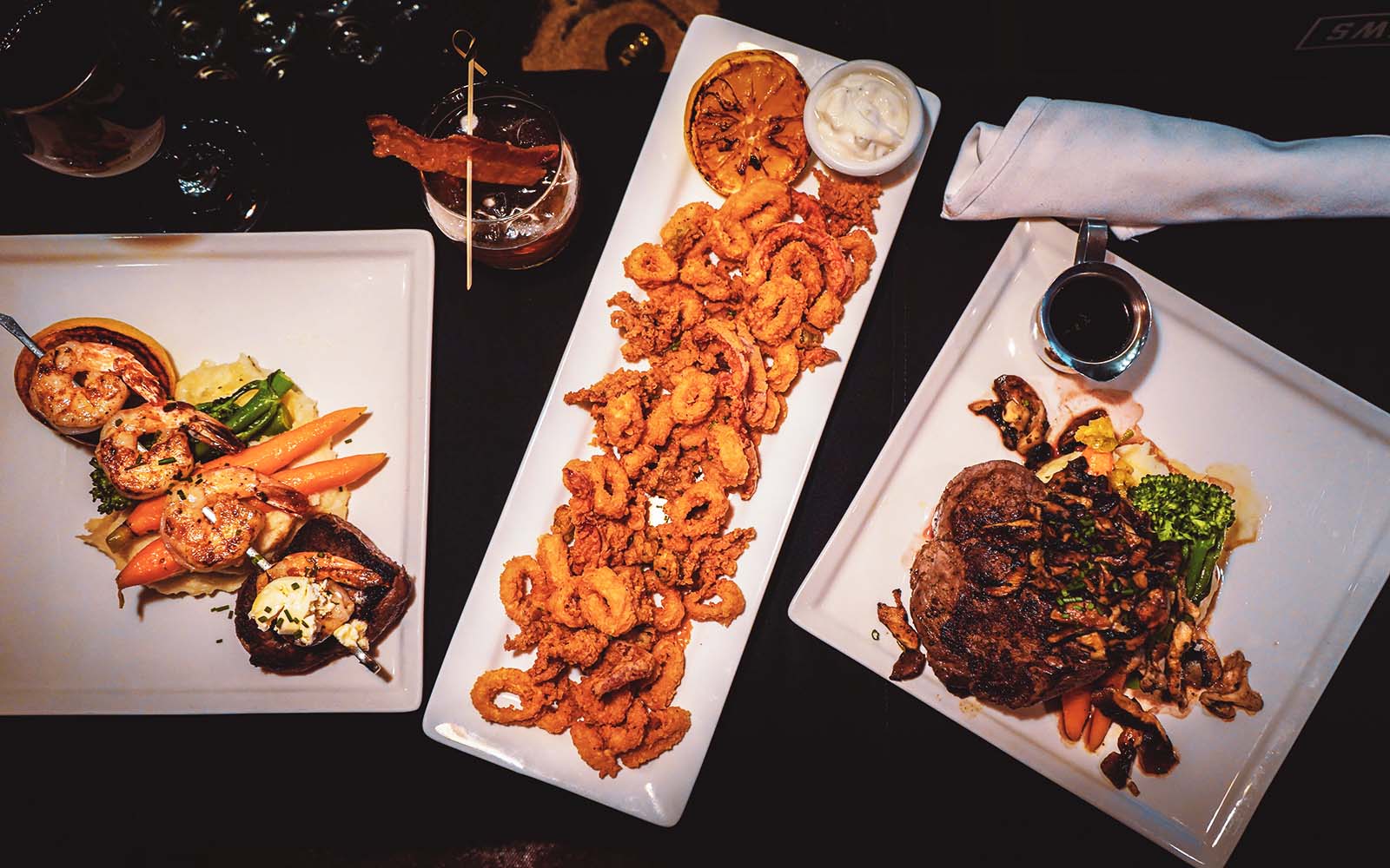 Table set with plated food including shrimp skewer, calamari and shrimp.