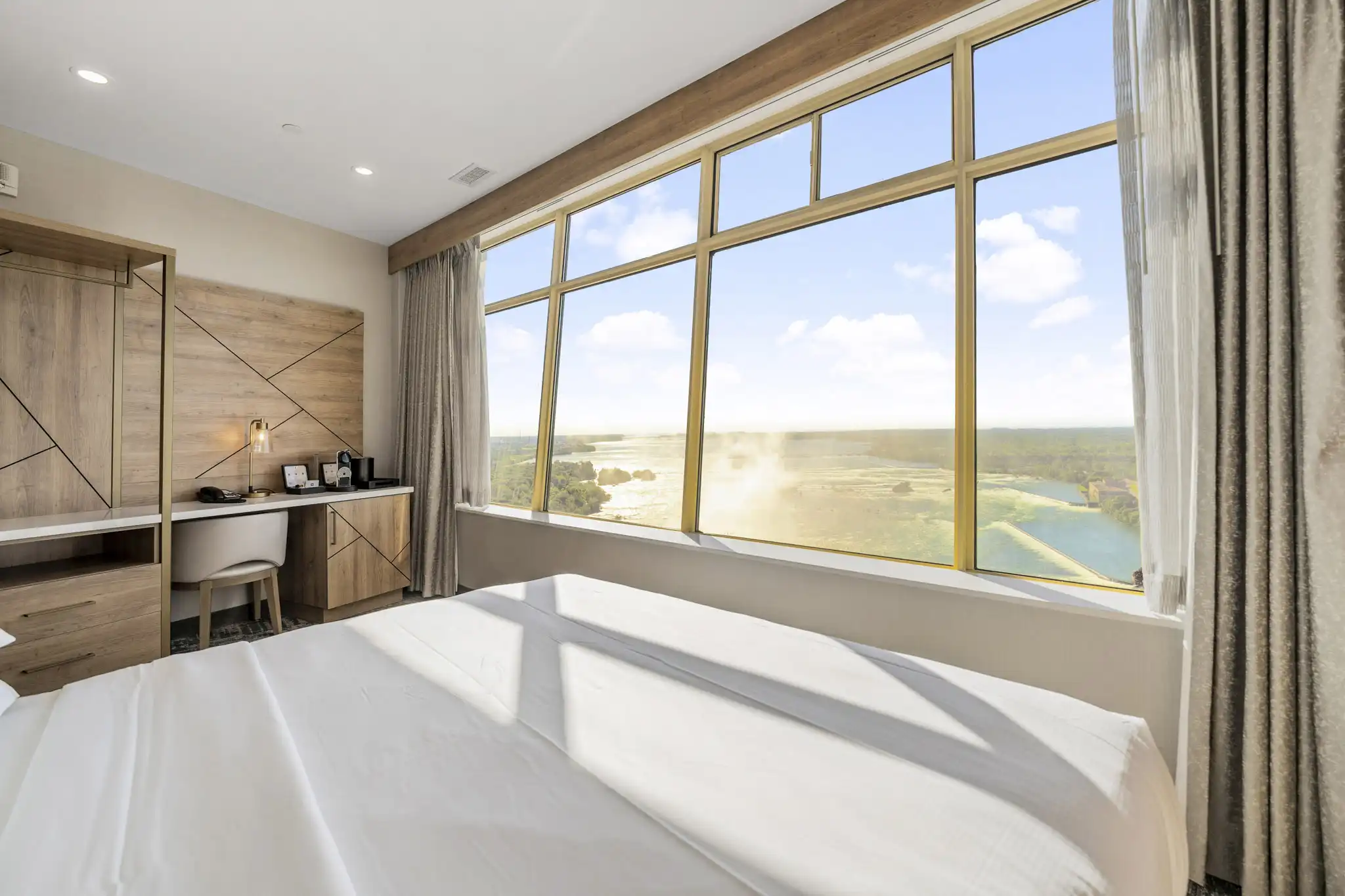 Hotel room with expansive window offering scenic view of Niagara Falls and Niagara river