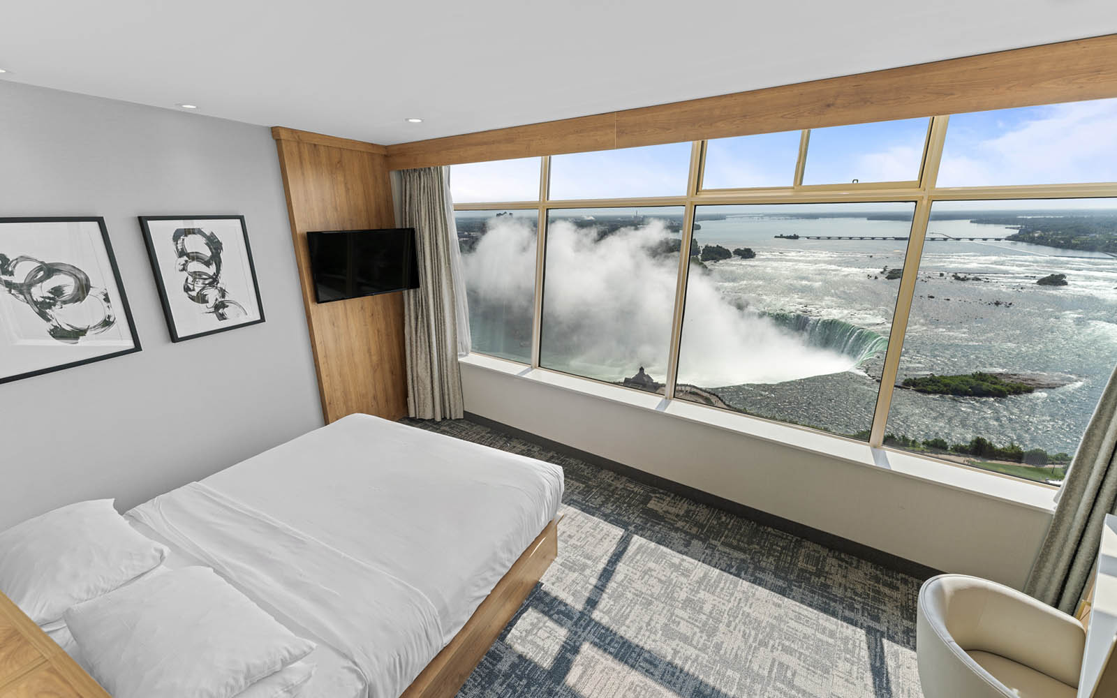 Hotel room with King Bed with white linens, expansive window offering scenic views of Niagara Falls